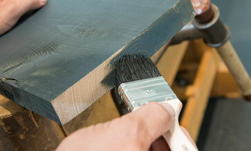 A selection of Osmo coatings, tools and accessories in front of wall panelling