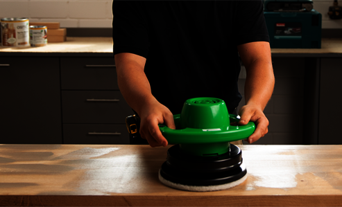 worker treats a wood surface with Osmo HandXcenter in a workshop